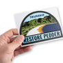 Hand holding bumper sticker for the restoration of Tasmania's Lake Pedder