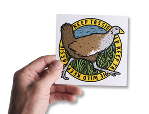 Male hand holding up bumper sticker of Tasmania's native hen (turbo chook) 